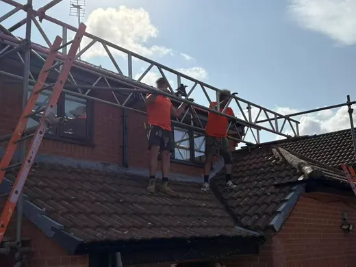 Two installers fitting mounting rails on a tiled roof